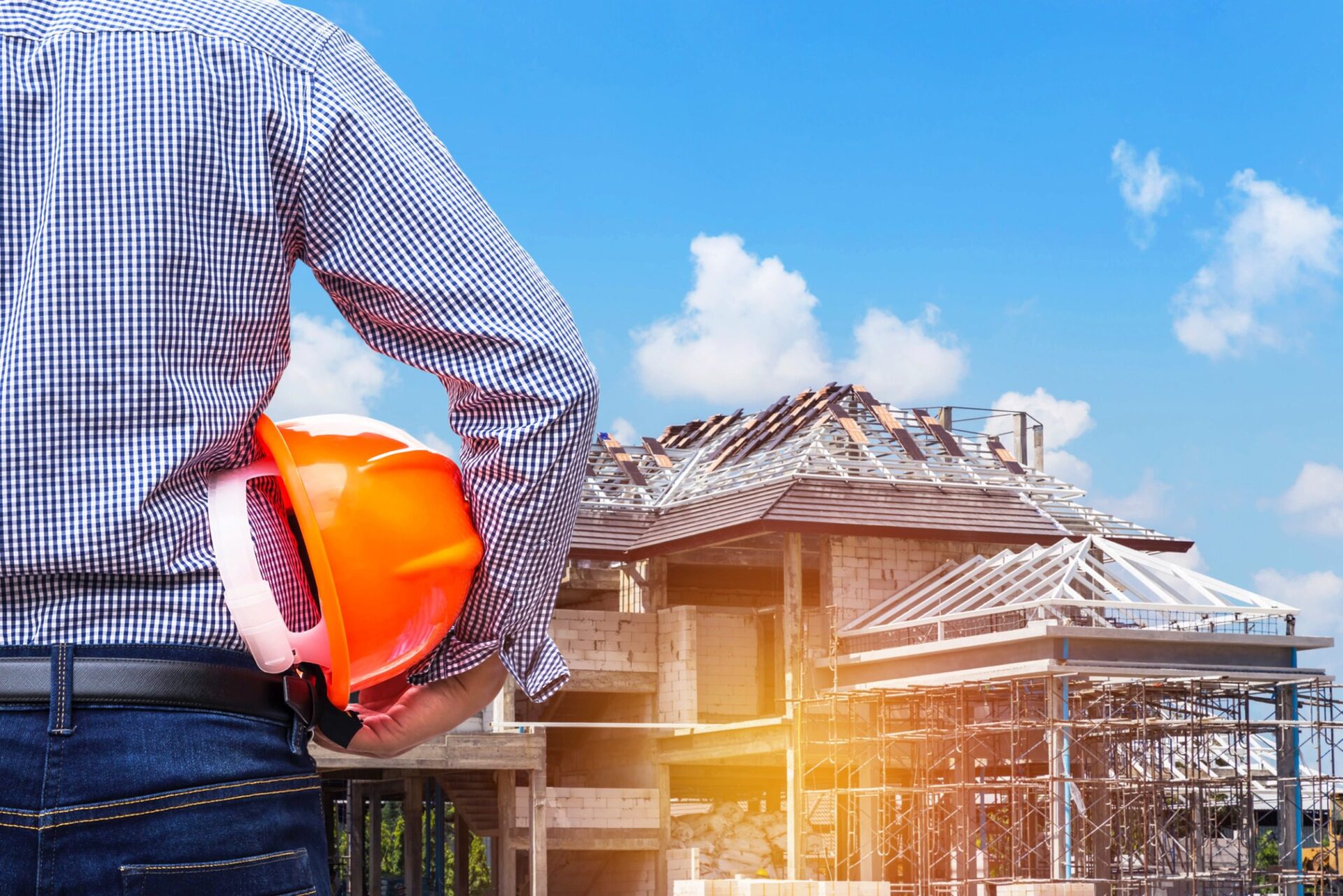 Engineer holding yellow safety helmet at new home building under construction site Engineer holding yellow safety helmet at new home building under construction site